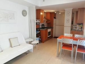 a living room and kitchen with a white couch and a table at APCOSTAS Marina D'or 1era línea - vista lateral mar in Oropesa del Mar