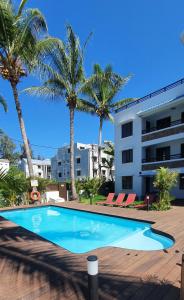 einem Pool vor einem Gebäude mit Palmen in der Unterkunft Les Cerisiers - Exclusive Beach Residence - 3 Bedroom Modern Apartment, Flic en Flac in Flic-en-Flac