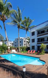 a swimming pool in front of a building with palm trees at Les Cerisiers - Exclusive Beach Residence - 3 Bedroom Modern Apartment, Flic en Flac in Flic-en-Flac