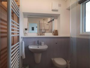 a bathroom with a sink and a toilet and a mirror at Eastcliff Escape Folkestone in Folkestone