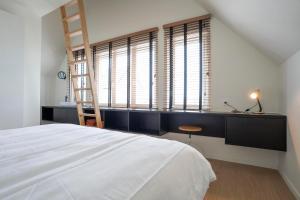 a bedroom with a bed and a desk and windows at stek&stoof in Sint-Pauwels