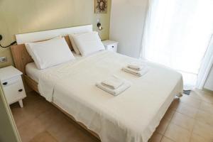 a bedroom with a white bed with towels on it at Delfini Villa, beachfront 2-bdrm maisonette in Possidi