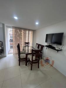 una sala da pranzo con tavolo, sedie e TV di Apartamento de Henry y Rita a Barranquilla