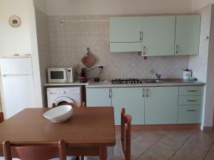 a kitchen with white cabinets and a wooden table at Casa Deidda in Villaputzu