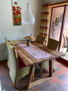 a wooden table with chairs and a vase of flowers on it at Ferienwohnung "Leevhuus" in Glücksburg