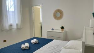 1 dormitorio blanco con 2 pares de zapatillas en una cama en La Casetta sul Golfo, en Sferracavallo