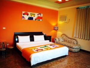 台東市的住宿－東椿民宿，一间卧室配有一张带橙色墙壁的大床