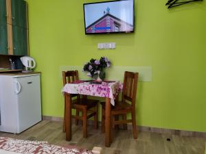 une table avec des chaises et une télévision sur un mur vert dans l'établissement Willa u Damiana - pokoje noclegi nad morzem, à Mielno