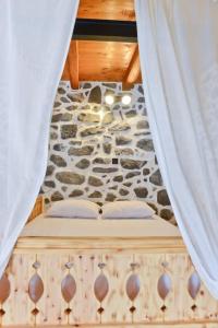 a bed in a room with a stone wall at Volcano View Nisyros in Emporeiós