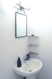 een badkamer met een witte wastafel en een spiegel bij Volcano View Nisyros in Emporeiós