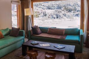 a living room with a couch and a table and a window at Galileo Boutique Hotel in San Carlos de Bariloche