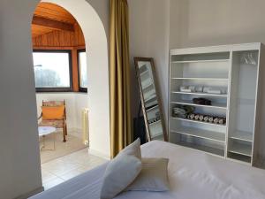una camera con letto bianco e armadio con bottiglie di vino di Camere Villa Lunardini a Frassinetto
