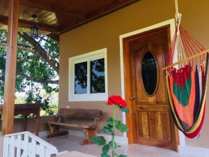 a house with a porch with a swing and a door at Hilamito Lodge in Tela