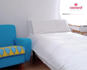 1 cama y 1 silla azul en una habitación en Apartamento Caracol - CORDOBA en Córdoba