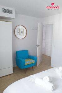 a blue chair in a room with a bed at Apartamento Caracol - CORDOBA in Córdoba