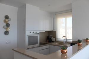 a white kitchen with a stove and a sink at Calpe Beachview in Calpe