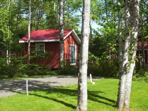 a red cabin with a red roof in the woods at New Glasgow Highlands Campground cabins in New Glasgow