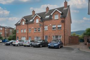 a large brick building with cars parked in front of it at Central Belfast Apartments: Ashley Mews in Belfast