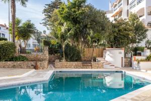 a swimming pool in a yard with trees and a building at Clube do Lago Hotel in Estoril