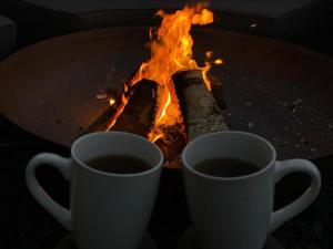 zwei Tassen Kaffee neben einem Tisch mit Kamin in der Unterkunft Hazel Cottage in Tenby