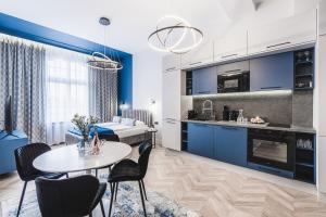 a kitchen and living room with blue cabinets and a table at Apartament 21A- Hvile Stay in Toruń