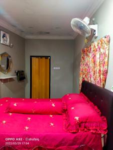 Una cama con colcha roja con estrellas doradas. en Ulya Homestay 3, en Jertih
