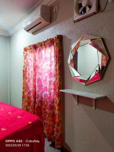 un espejo colgado en una pared junto a una cama en Ulya Homestay 3, en Jertih