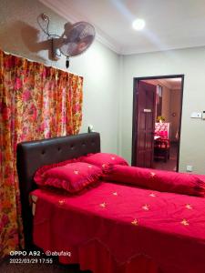 1 dormitorio con 1 cama con sábanas rojas y ventilador en Ulya Homestay 3, en Jertih