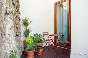 a balcony with potted plants and a table and chair at 14 Calçada de Santiago in Vila do Conde