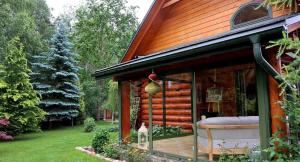 una casa con un porche con un banco en un patio en Willa Siemianówka - Sauna, Jacuzzi en Rybaki