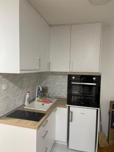 a kitchen with white cabinets and a sink and a microwave at Stan centar ns in Novi Sad