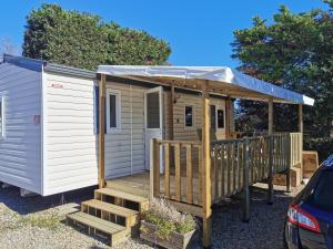 a tiny house with a porch and a deck at Mobil-Home en camping**** in Vic-la-Gardiole