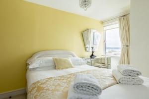 a bedroom with a bed with yellow walls and a window at Ocean Escape in Poole