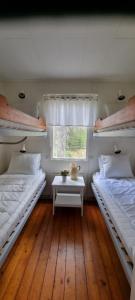 duas camas num quarto com uma mesa e uma janela em Rolfskärrs Stugby em Nygård