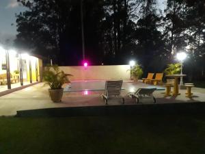 a patio with two chairs and a pool at night at Sítio Toa Toa in São Roque