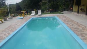 a blue swimming pool with chairs in a yard at Sítio Toa Toa in São Roque