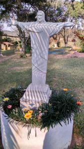 a statue of a christ redeemer in a park with flowers at Sítio Toa Toa in São Roque