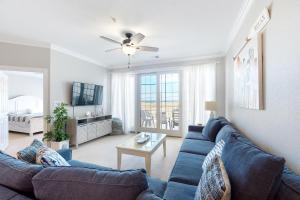 Una sala de estar con un sofá azul y una mesa. en The Sandbridge Dunes - Salty Mermaid 110, en Virginia Beach
