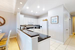 a kitchen with white cabinets and a black counter top at The Sandbridge Dunes - Salty Mermaid 110 in Virginia Beach