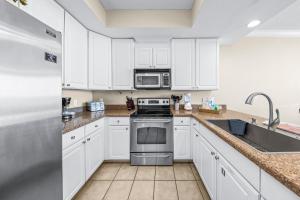 una cocina con armarios blancos y electrodomésticos de acero inoxidable en San Carlos Unit 607, en Gulf Shores