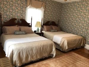 two beds in a bedroom with floral wallpaper at Guilford Bed and Breakfast in Guilford