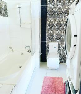 uma casa de banho com uma banheira branca e um WC. em Jaunā Teika Penthouse em Riga