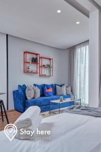 a living room with a blue couch and a bed at Stayhere Casablanca - Palmier - Executive Residence in Casablanca