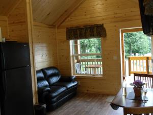 a living room with a leather couch in a log cabin at Camperland Bridal Falls RV Resort & Cabins in Rosedale