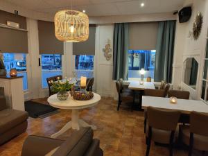 ein Wohnzimmer mit einem Tisch, Stühlen und Fenstern in der Unterkunft Hotel Sfinx in De Panne