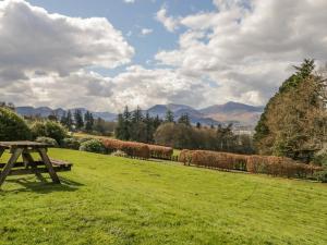 a picnic table in a field with mountains in the background at Garden Cottage in Keswick