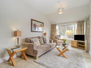 ein Wohnzimmer mit einem Sofa und einem TV in der Unterkunft Garden Cottage in Keswick