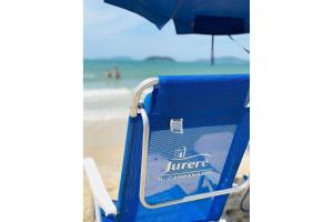 uma cadeira de praia azul com um guarda-sol numa praia em Cobertura luxuosa dentro de Resort - Direto com proprietário - ILCMASTER em Florianópolis