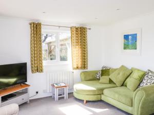 a living room with a green couch and a television at Hunrosa in Redruth