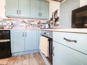 a kitchen with white cabinets and a sink and a microwave at Hunrosa in Redruth